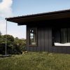 Rear view of house showing rain chain the collects water in basin and sends to Acer/Pioneer water tanks. Outdoor bathing room features KOHLER soaking tub and overhead rain shower. Cedar window trim around Andersen windows (made of recycled materials). Standing seam metal roof has Sunflare solar panels hidden between the seams.
